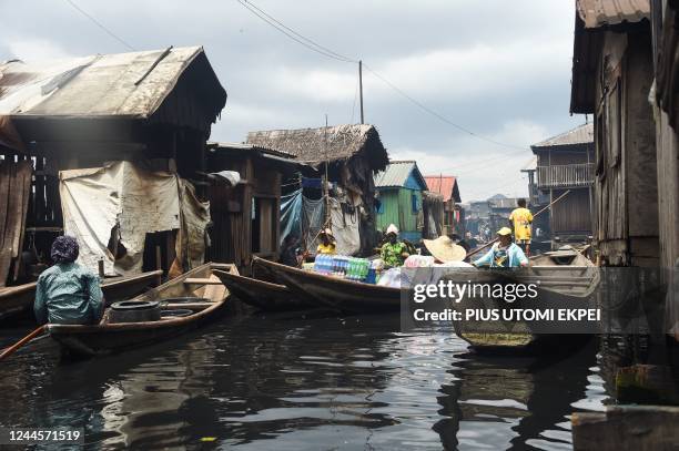 People ferry wares in pirogues in the slum community of Makoko in Lagos, Nigeria's commercial capital, on October 19, 2022. - With the UN forecasting...