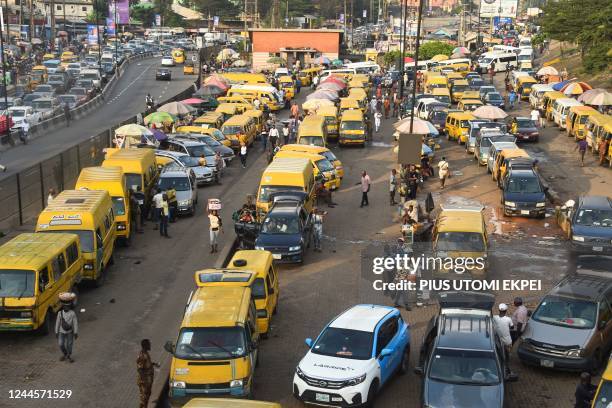 Vehicles drive in chaotic traffic gridlock past yellow painted mini buses, popularly called Danfo, parked at Ojodu-Berger bus station in Lagos,...