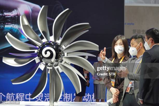 This photo taken on November 5, 2022 shows a staff member introducing an aircraft engine model on display for visitors at the General Electric stand...