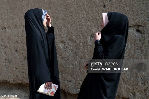 Afghan Hazara girls gesture along a street in Dasht-e-Barchi in Kabul on November 7, 2022.