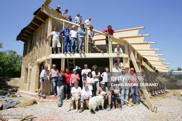 Les bénévoles de l'association terre de vent posent le 07 juin 2006 à Athée devant la maison bioclimatique qu'ils fabriquent à partir de paille, de...