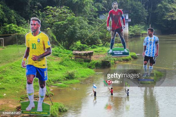 Fans wave flags next to the giant cutouts of players from Brazil's Neymar , Portuguese Cristiano Ronaldo and Argentine Lionel Messi, erected by...