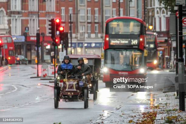 Red London bus seen behind a 1901 Darracq veteran car at Clapham Common in South London. More than 350 veteran cars took part in the annual RM...
