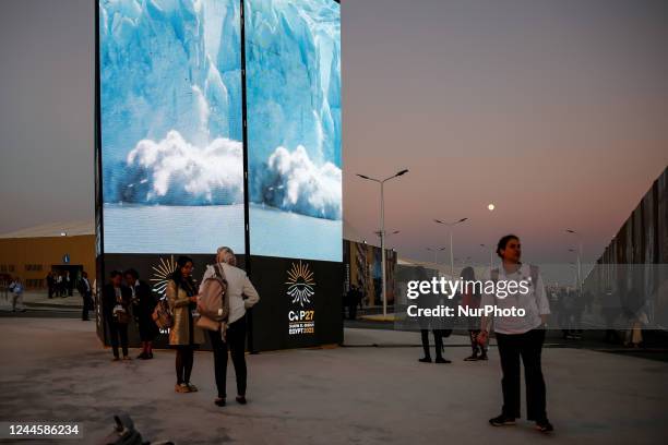 Participants walk in front of a screen with the COP27 logo on the second day of the COP27 UN Climate Change Conference, held by UNFCCC in Sharm...