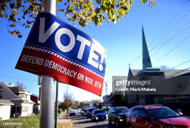 Cars drive beneath a placard that states "VOTE DEFEND DEMOCRACY on NOV. 8th" affixed to street pole the day before the midterm general election on...