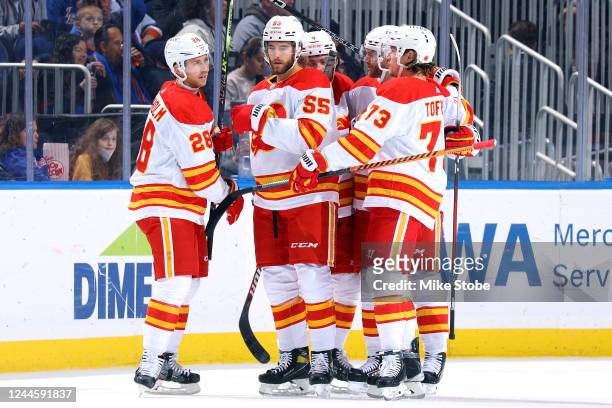 Elias Lindholm of the Calgary Flames is congratulated by his teammates after scoring a goal against the New York Islanders during the first period at...