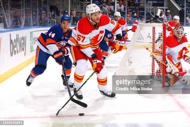Jean-Gabriel Pageau of the New York Islanders and Nick DeSimone of the Calgary Flames battle for the puck during the first period at UBS Arena on...