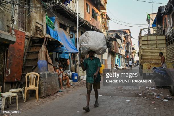 In this photograph taken on November 2 a worker carries a load during morning hours in the Dharavi slums of Mumbai. - India is projected to see an...