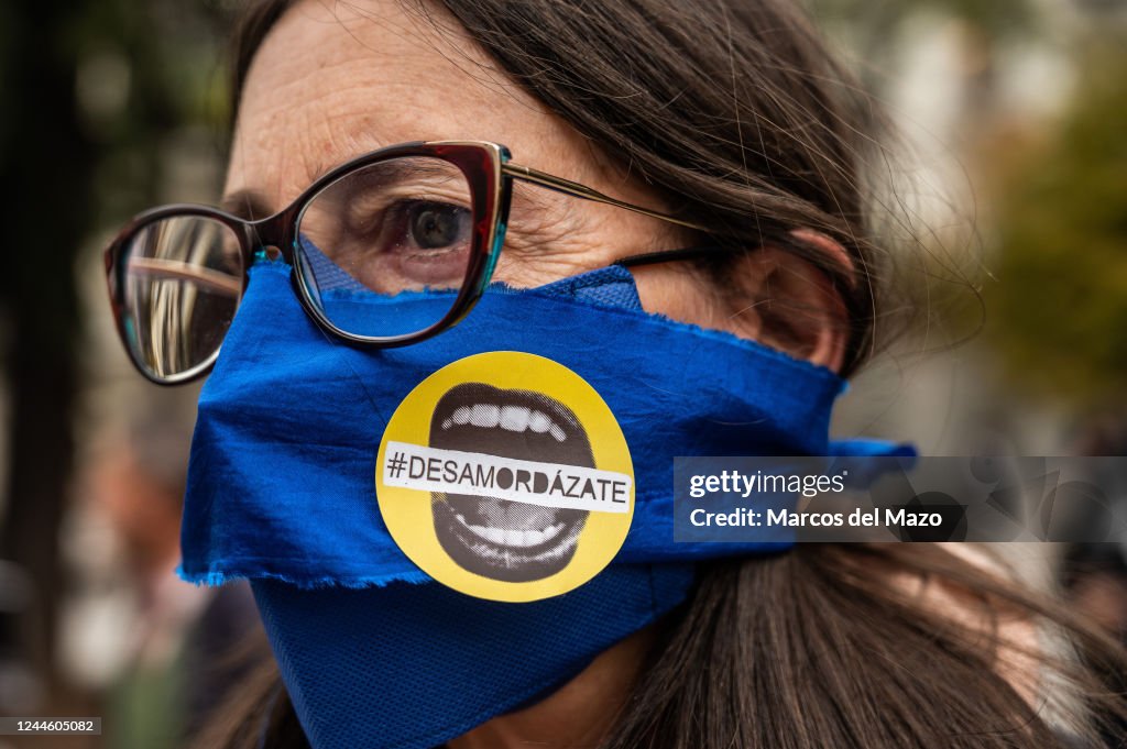 A woman with her mouth gagged and a sticker reading 'ungag'...