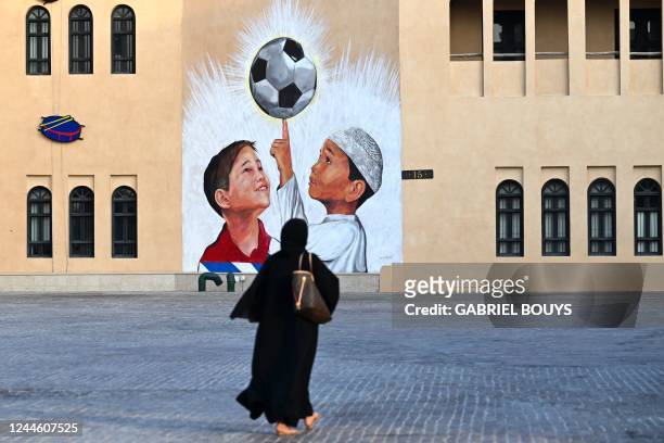 Woman walks past a mural in Doha on November 8 ahead of the Qatar 2022 FIFA World Cup football tournament.