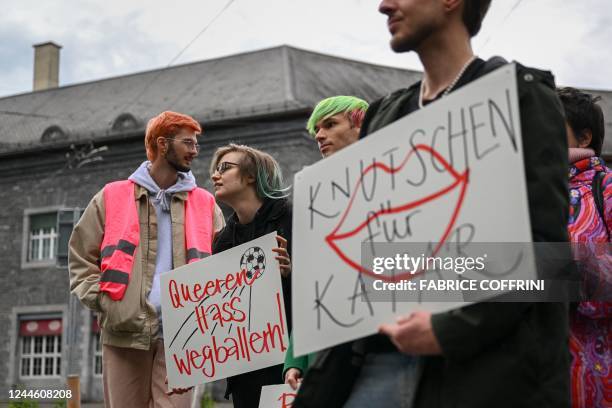 Activists hold boards reading in German "shooting at queer hate" and "Smooching for Qatar" during a symbolic action by LGBT+ associations in front of...