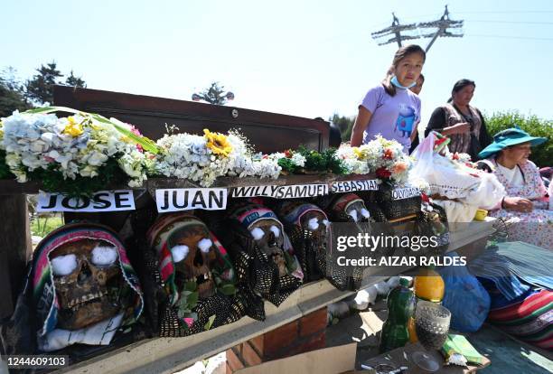 Members of the Quiste family stand next to 'ñatitas' at the general cemetery in La Paz on November 8 as Bolivia celebrates the annual Natitas...