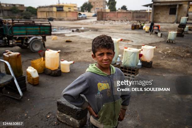 Syrian boy waits for customers as he sells diesel on a roadside in the opposition held Syrian city of Raqa on November 8 amid a fuel crisis in...