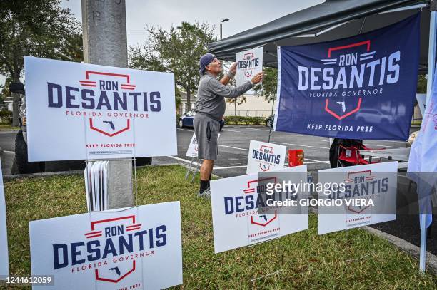 Carlos Crespo hangs signs in support of Florida State Governor Ron Desantis, outside a polling site in St Petersburg, Florida, on November 8, 2022.