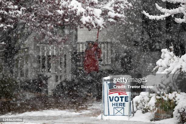 Washoe County employee uses a shovel to knock snow off of trees outside of a vote center on November 8, 2022 in Reno, Nevada. After months of...