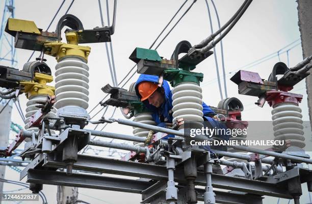 Electricians work on the maintenance of power lines at an energy transforming power station in the outskirts of Balti city November 2, 2022. - Faced...