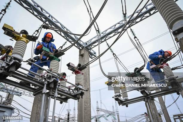 Electricians work on the maintenance of power lines at an energy transforming power station in the outskirts of Balti city November 2, 2022. - Faced...