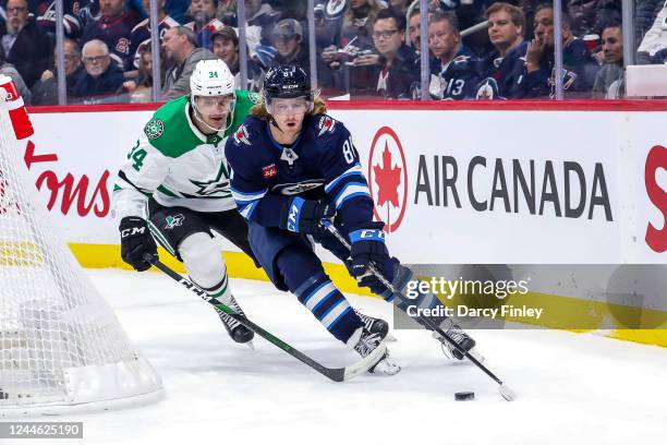 Kyle Connor of the Winnipeg Jets plays the puck around the net as Denis Gurianov of the Dallas Stars gives chase during first period action at the...