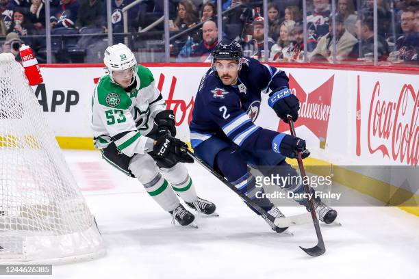 Dylan DeMelo of the Winnipeg Jets plays the puck around the net as Wyatt Johnston of the Dallas Stars gives chase during second period action at the...