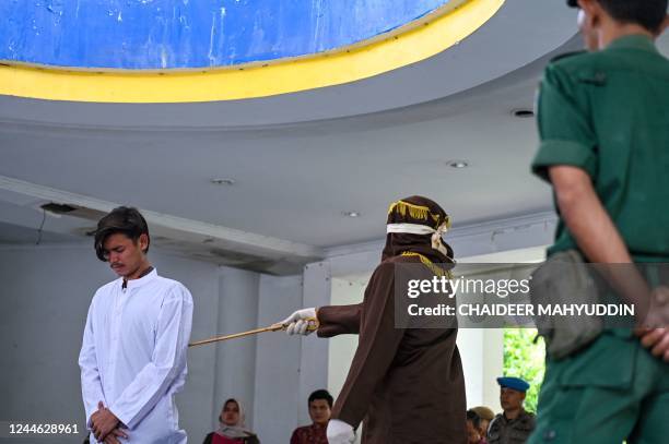 Man is publicly caned by a member of the Sharia police as punishment under Aceh province's Sharia laws for being caught in close proximity with a...