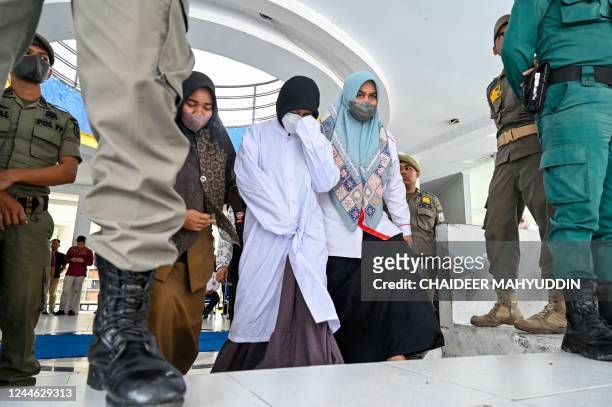 Woman is escorted by members of the Sharia police after being caned as punishment for being caught in close proximity with a man in Banda Aceh on...