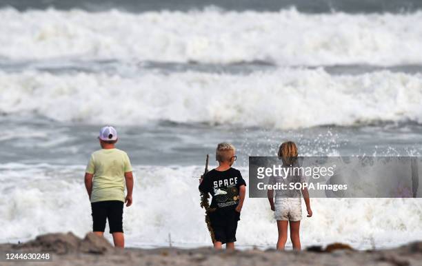 Children watch the rough surf at Cocoa Beach, Florida, as Tropical Storm Nicole approaches the east coast of Florida. The storm is on track to...