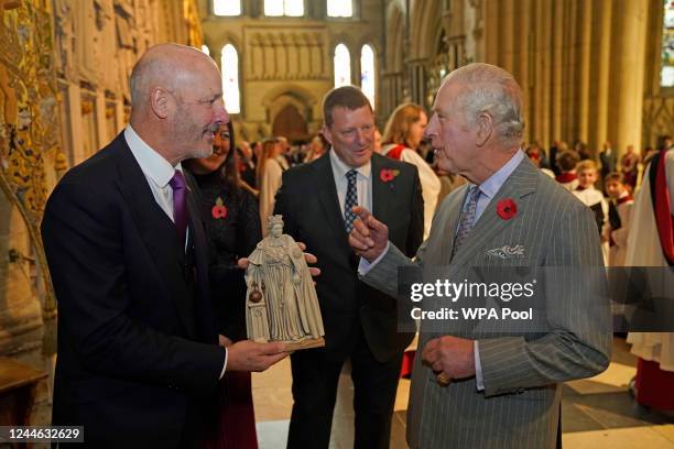 King Charles III of the United Kingdom is presented with a maquette of the statue of Queen Elizabeth II that he will unveil later during a visit to...