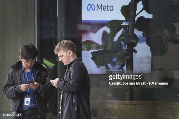 People using their mobile phones outside the offices of Meta, the parent company of Facebook and Instagram, in King's Cross, London. Meta has...