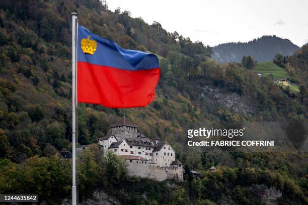 Picture taken on October 28, 2022 shows the flag of Liechtenstein floating next to Vaduz Castle, the palace and official residence of the Prince of...