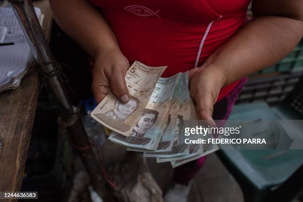 Woman counts Bolivar bills in a street market at the Jose Felix Ribas community in the Petare neighborhood in Caracas on November 5, 2022. -...