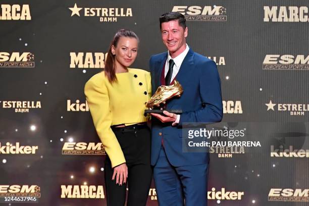Barcelona's Polish forward Robert Lewandowski poses for pictures holding the Golden Boot trophy with his wife Polish athlete Anna Lewandowska during...
