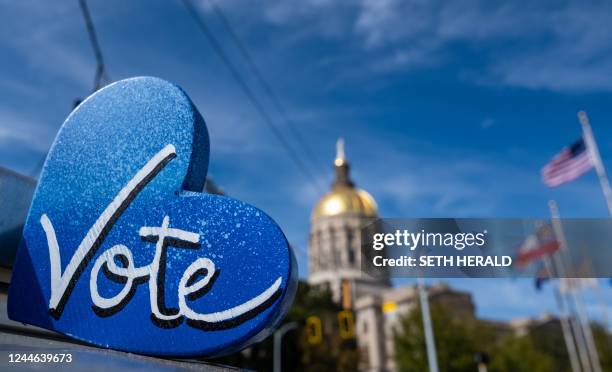 The Georgia State Capitol building is seen behind a "Vote" sign, a day after the US midterm election, in Atlanta, Georgia, on November 9, 2022. - The...