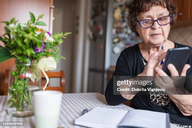 woman wearing eyeglasses when looking at smart phone - grandparent phone stock pictures, royalty-free photos & images