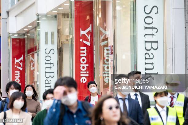 This picture taken on November 9, 2022 shows people walking past a mobile shop for Japan's SoftBank in Tokyo. - Softbank Group are expected to...