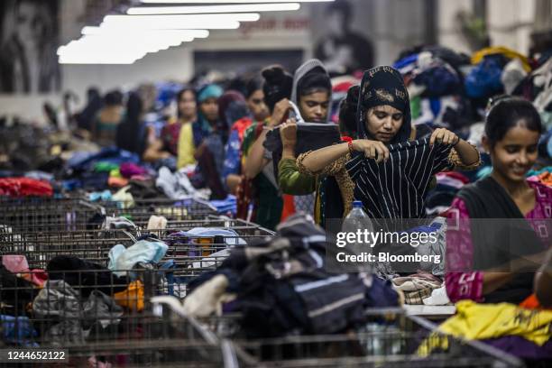 Workers sift through piles of clothes at the sorting area of the factory floor at Canam International Pvt., in Kandla, India, on Friday, Sept. 9,...