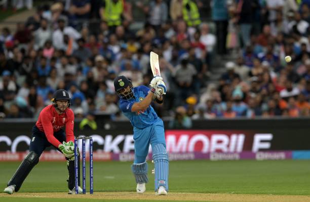 India's Virat Kohli hits a boundary as England's wicketkeeper and captain Jos Buttler looks on during the ICC men's Twenty20 World Cup 2022...