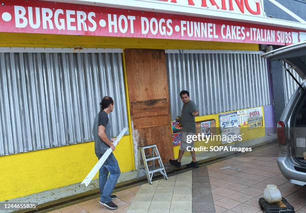 Workers cover the windows of a restaurant on the boardwalk in Daytona Beach in Florida, as tropical Storm Nicole approaches the coast of Florida with...