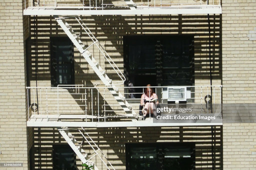 Woman reading on her fire escape during Coronavirus shutdown