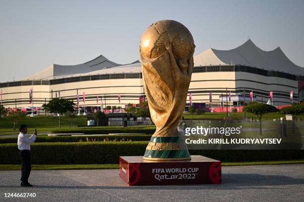 Man takes a picture of a FIFA World Cup trophy replica in front of the Al-Bayt Stadium in al-Khor on November 10 ahead of the Qatar 2022 FIFA World...