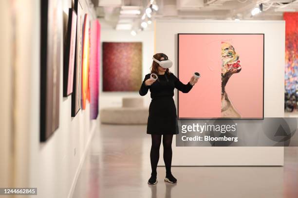 Gallery assistant wearing an Oculus Quest 2 virtual reality headset to view the House of Fine Art Metaverse gallery stands next to the "VLADINSKY,...