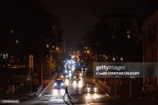 Pedestrian crosses a street during a power cut in downtown Kyiv on November 10 amid the Russian invasion of Ukraine. - For much of the past month,...