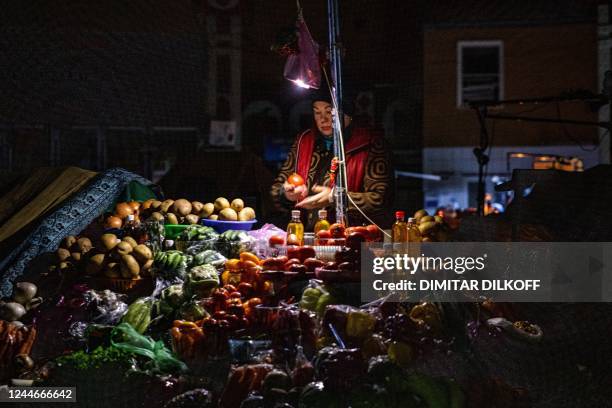 Vendor waits for customers during a power cut at Bessarabsky market in downtown Kyiv on November 10 amid the Russian invasion of Ukraine. - For much...