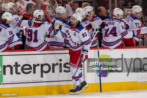 Mika Zibanejad of the New York Rangers pounds gloves with teammates on the bench after scoring a goal during the first period of an NHL game against...