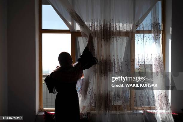 In this photograph taken on October 15 Maryam adjusts the curtains of a window during an interview with AFP at a house in Charikar, Parwan province....