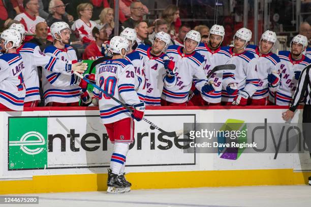 Chris Kreider of the New York Rangers pounds gloves with teammates on the bench after scoring a goal during the second period of an NHL game against...