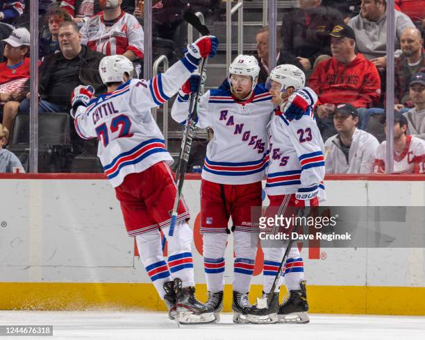 Alexis Lafrenière and Filip Chytil of the New York Rangers congratulate teammate Adam Fox after he scores a goal during the third period of an NHL...