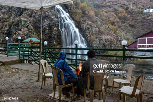 Kashmiri men gather around a bonfire to keep themselves warm near the Drang waterfall during a cold autumn day in Drang about 40kms north of...
