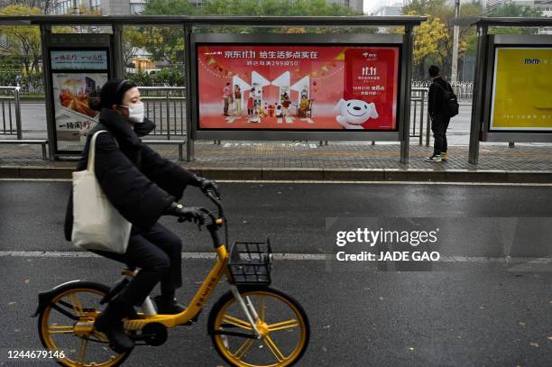 Woman cycles past billboards promoting the annual "Singles Day" shopping event, also known as the Double 11, at a bus stop in Beijing on November 11,...