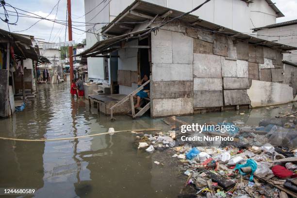 Residents wade through a flooded alley by tidal waves in Jakarta's coastal area on 11 November 2022. Over the last 30 years, the northern parts of...