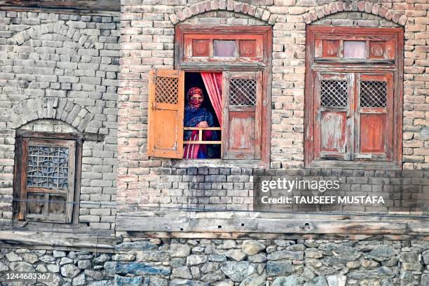 Woman looks out from a window of a house as a Muslim cleric displays a relic marking the last friday of 'urs', or death anniversary of the sufi saint...